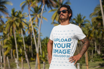 T-Shirt Mockup of a Tattooed Man Standing by Palm Trees 