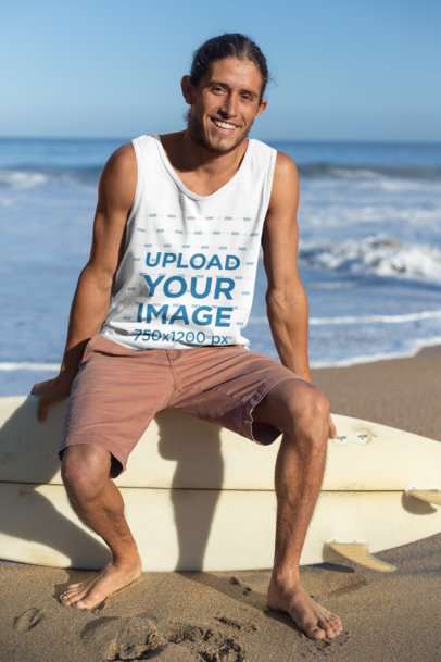 Tank Top Mockup of a Smiling Man with Tied Hair Sitting over His Surfboard at the Beach