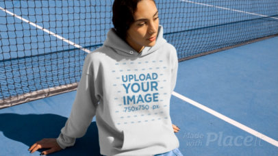 Hoodie Video Featuring a Woman Sitting in a Tennis Court