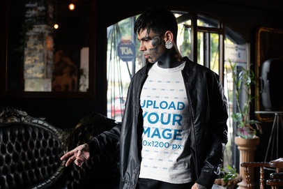 T-Shirt Mockup of a Goth Man with a Tattooed Face and Piercings Wearing a Jacket