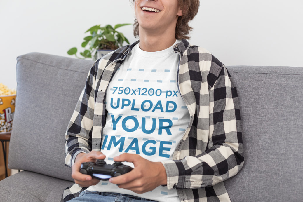 T-Shirt Mockup of a Young Man Happily Playing Video Games in His Living Room