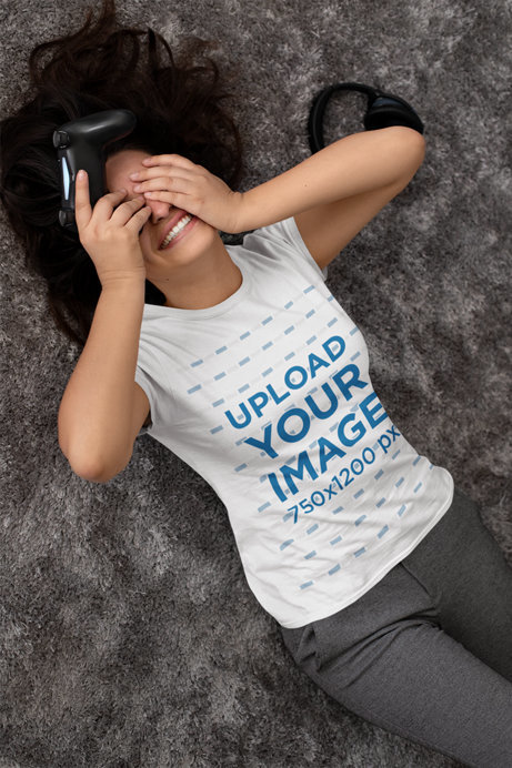 T-Shirt Mockup of a Gamer Woman Lying on a Carpet While Covering Her Face