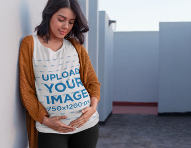 Tee Mockup of an Expecting Pregnant Woman Leaning Against a Wall