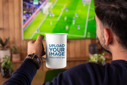 Mockup of a Man Watching a Soccer Match with a 21 oz Enamel Mug in His Hand 26939a