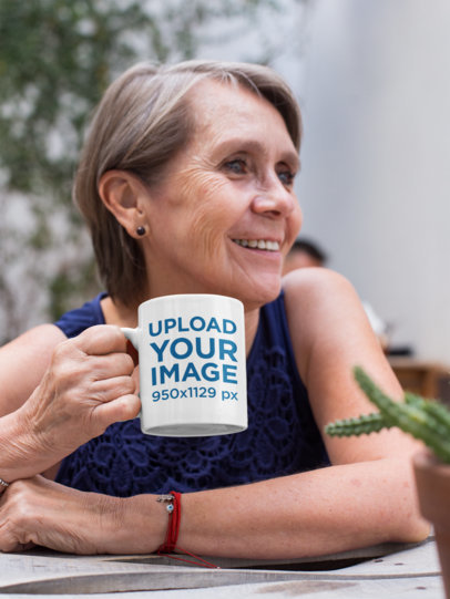 11 Oz Mug Mockup Featuring a Smiling Elderly Woman at a Table
