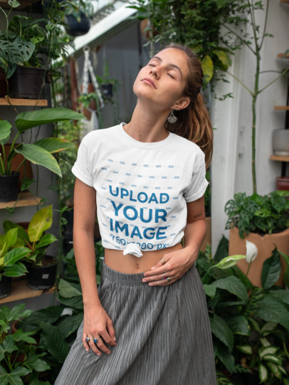 Mockup of a Young Woman Wearing a Knotted T-Shirt by Some Plants