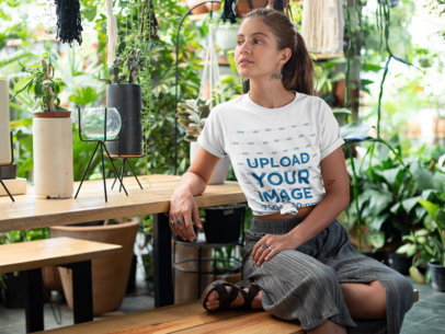 Knotted Tee Mockup Featuring a Relaxed Woman in a Greenhouse 