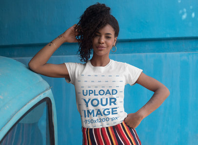 Tee Mockup of a Cool Woman with Curly Hair Posing in Front of a Blue Wall 27348