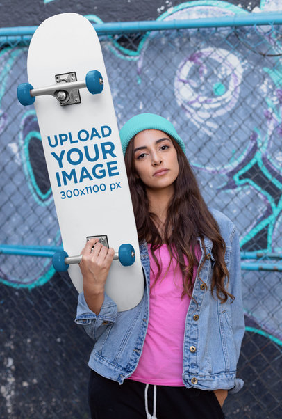 Skateboard Mockup of a Young Woman Against a Chain Link Fence
