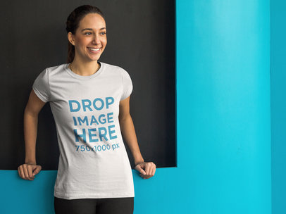 T-Shirt Mockup of a Woman Standing in Front of a Blue Wall 