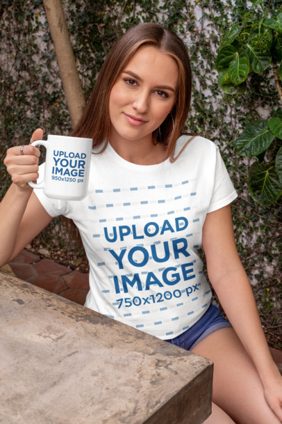 Mockup of a Woman with a Crewneck T-Shirt Holding a 15 oz Mug at a Concrete Table 27512