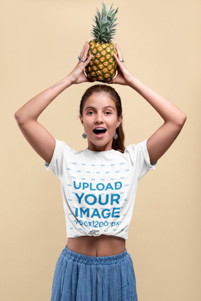Mockup of a Woman Wearing a Knotted Tee While Holding a Pineapple over Her Head