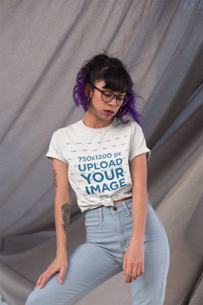 Knotted T-Shirt Mockup of a Woman with a Tattooed arm Against a Wavy Fabric