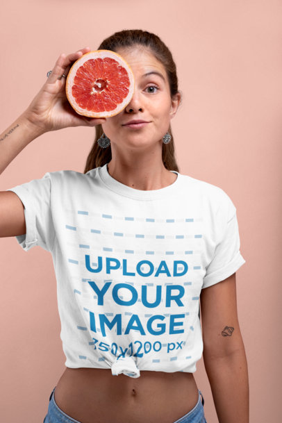 Knotted Tee Mockup of a Woman Covering Half of Her Face with a Grapefruit