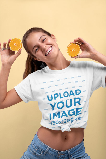 Knotted T-Shirt Mockup of a Smiling Woman Holding Two Halves of an Orange