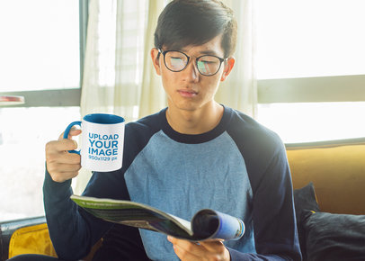 11oz Two-Toned Mug Mockup Featuring a Serious Young Man Reading 