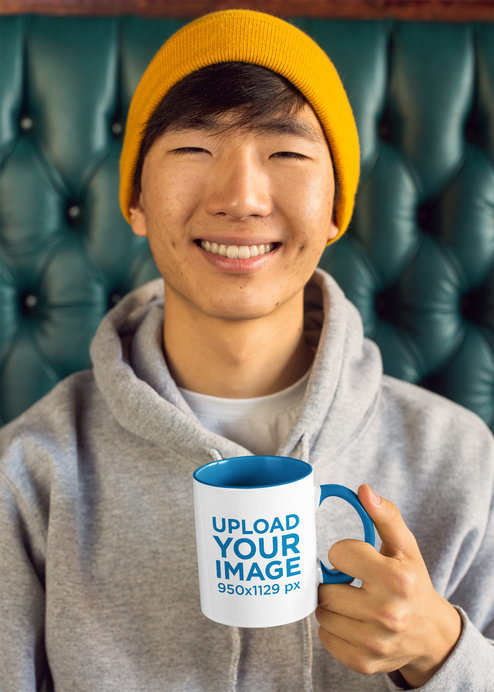 11 oz Two-Toned Mug Mockup of a Young Man Sitting on a Green Leather Couch 