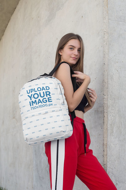 Backpack Mockup Featuring a Teenager Standing Next to a Concrete Wall 27711