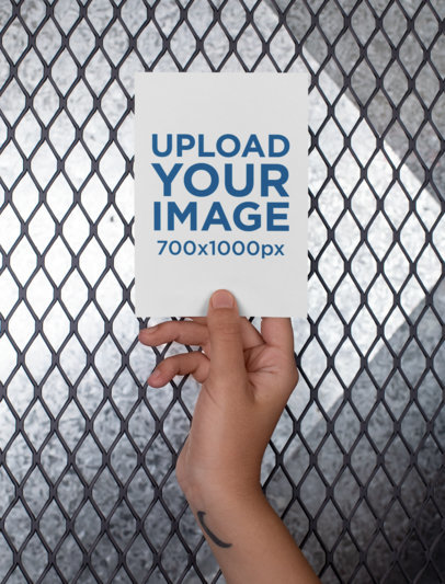 Mockup of an A6 Postcard Held Up Against a Fence