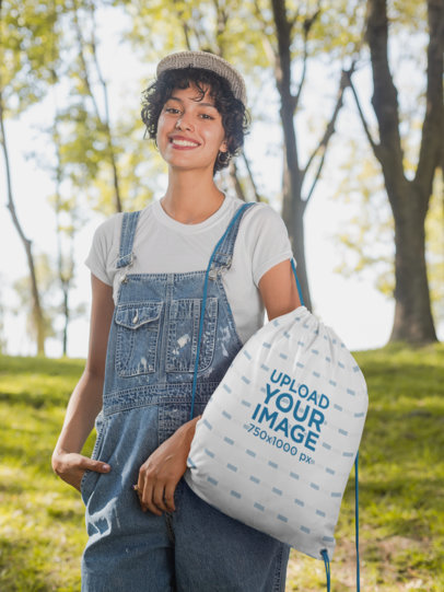 Drawstring Bag Mockup Featuring a Woman Wearing a Denim Overall in the Woods 27591