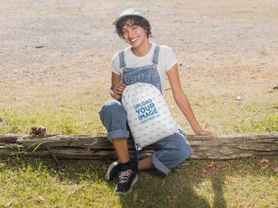 Drawstring Bag Mockup of a Woman Sitting on a Wood Log at the Countryside 27595