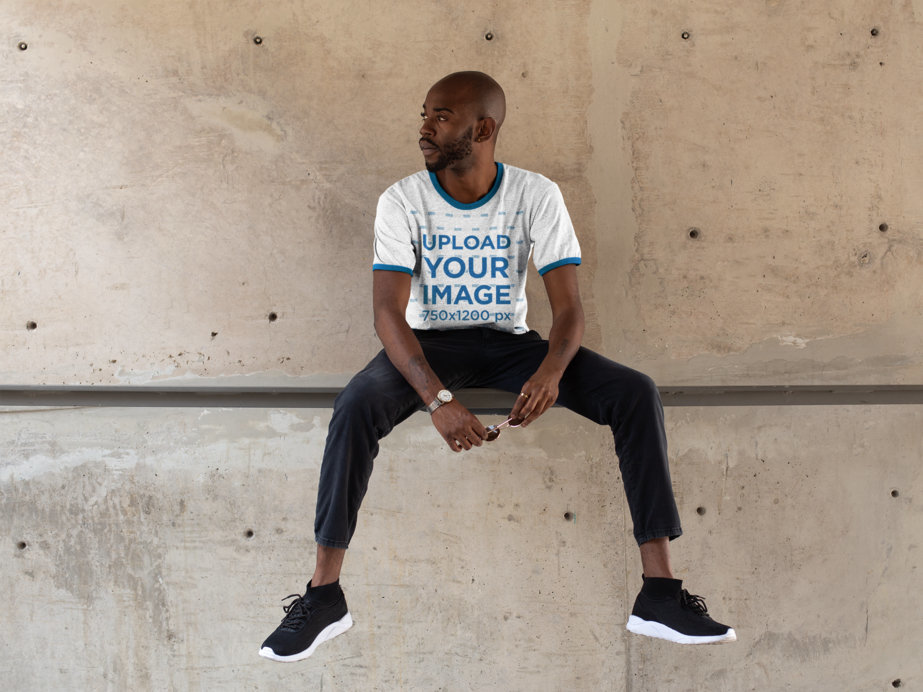 Ringer T-Shirt Mockup Featuring a Cool Young Man Against a Concrete Wall 