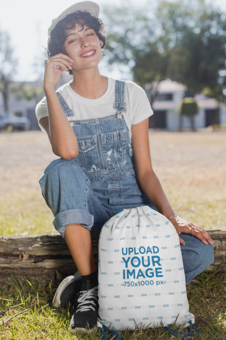 Drawstring Bag Mockup of a Happy Woman Sitting on a Wood Log