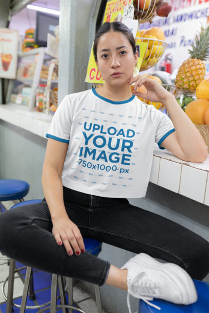 Ringer Tee Mockup Featuring a Woman Sitting on a Bench at a Market