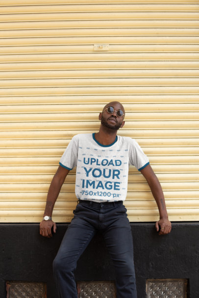 Ringer T-Shirt Mockup Featuring a Man Leaning Against a Wall