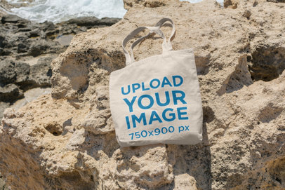 Mockup of a Tote Bag Lying on a Rock by the Sea 