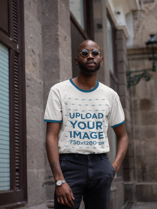 Ringer Tee Mockup of a Man with Sunglasses Posing by Some Stone Buildings