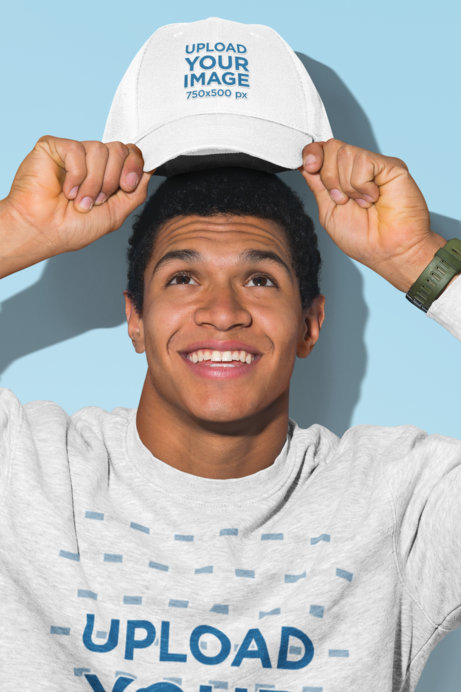 Mockup of a Man with a Crewneck Sweatshirt Holding a Dad Hat over His Head