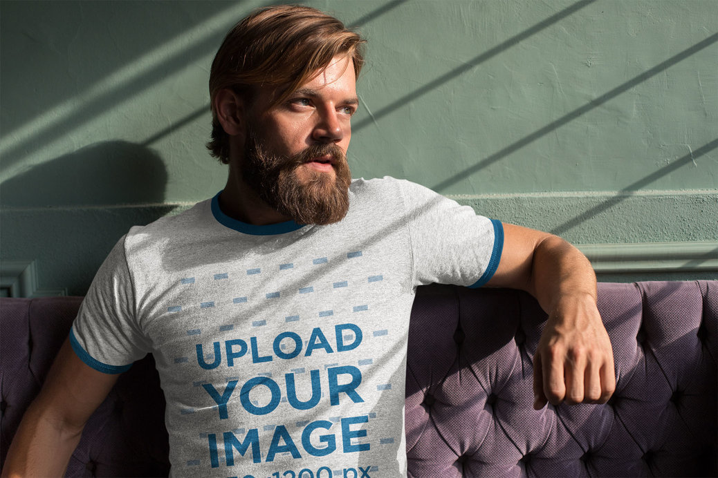 Ringer T-Shirt Mockup Featuring a Cool Bearded Man Sitting on a Purple Couch 