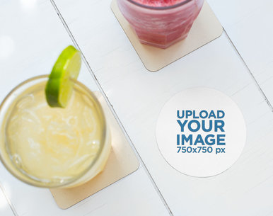 Mockup of a Round Coaster Next to a Lemonade over a White Wooden Surface