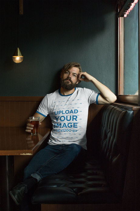 Mockup of a Bearded Man Wearing a Ringer Heathered T-Shirt Sitting on a Restaurant Couch