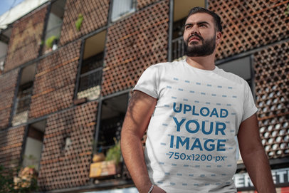Plus Size T-Shirt Mockup of a Bearded Man Posing Against a Modern Building 