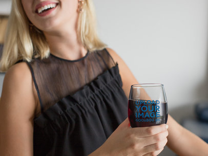 Mockup of a Blonde Woman Holding a Stemless Wine Glass