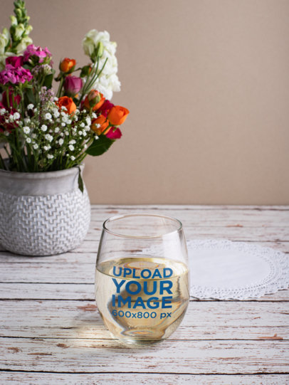 Stemless Wine Glass Mockup Over a Wooden Table by a Floral Centerpiece 27937