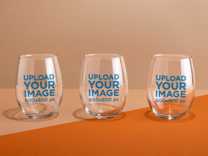 Mockup of Three Stemless Wine Glasses over a Bicolor Surface