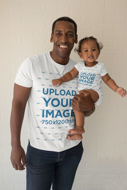 Mockup of a Smiling Man with a T-Shirt Holding Her Baby Girl in a Onesie