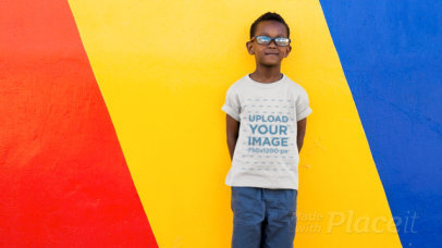 T-Shirt Video of a Happy Kid Posing Against a Colorful Wall 
