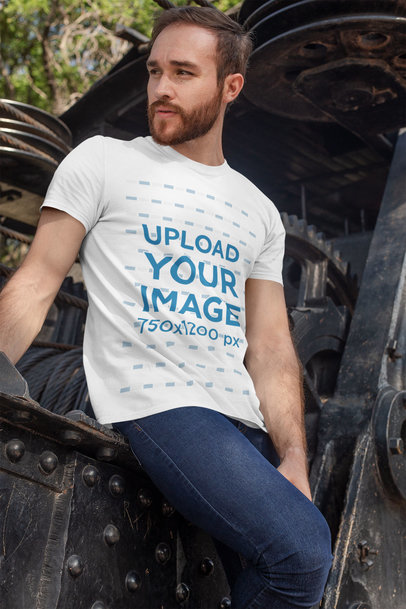 Tee Mockup Featuring a Bearded Man Leaning Against Some Old Industrial Machinery 28191
