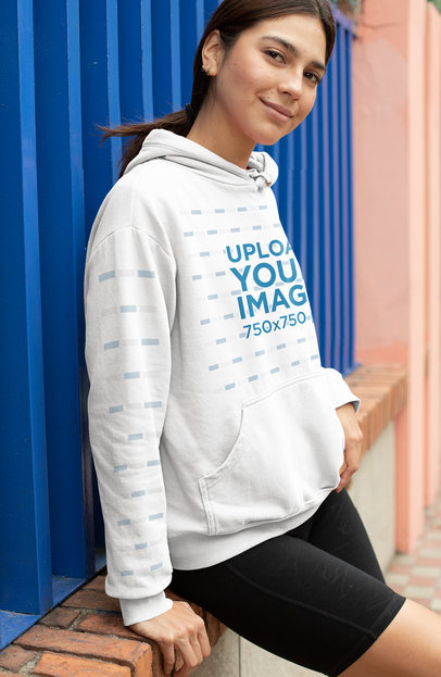 Hoodie Mockup with a Customizable Sleeve Featuring a Woman Leaning Over a Brick Wall