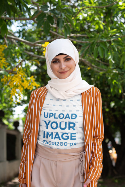 T-Shirt Mockup of a Woman with a Hijab Posing Under a Tree