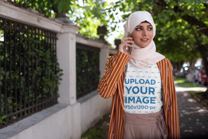 T-Shirt Mockup Featuring a Woman Wearing a Hijab While Using Her Mobile
