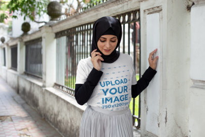 T-Shirt Mockup Featuring a Woman With a Hijab Walking on a Sidewalk 