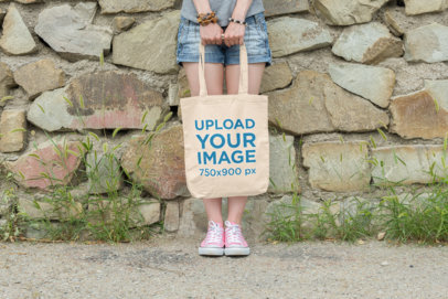 Tote Bag Mockup of a Woman Standing Against a Rock Wall