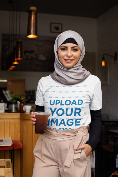 T-Shirt Mockup of a Woman Wearing a Hijab in a Restaurant