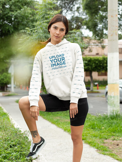 Pullover Hoodie Mockup with a Customizable Sleeve of a Woman by a Garden Street