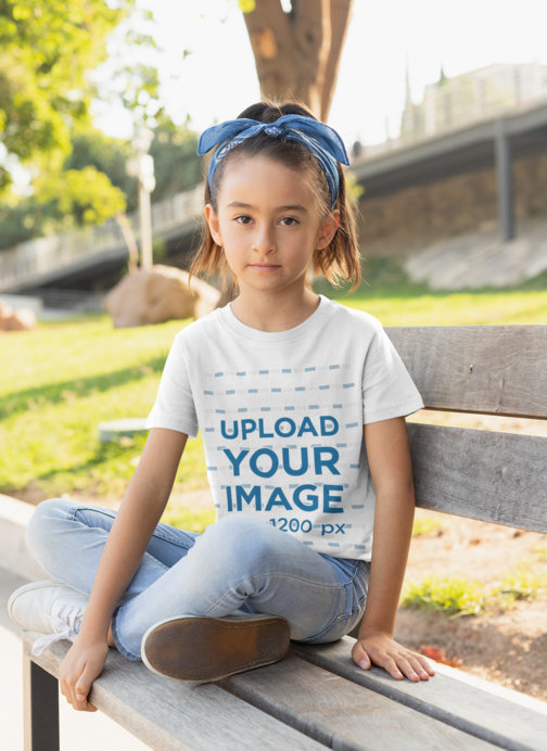 T-Shirt Mockup of a Girl Sitting on a Bench at the Park